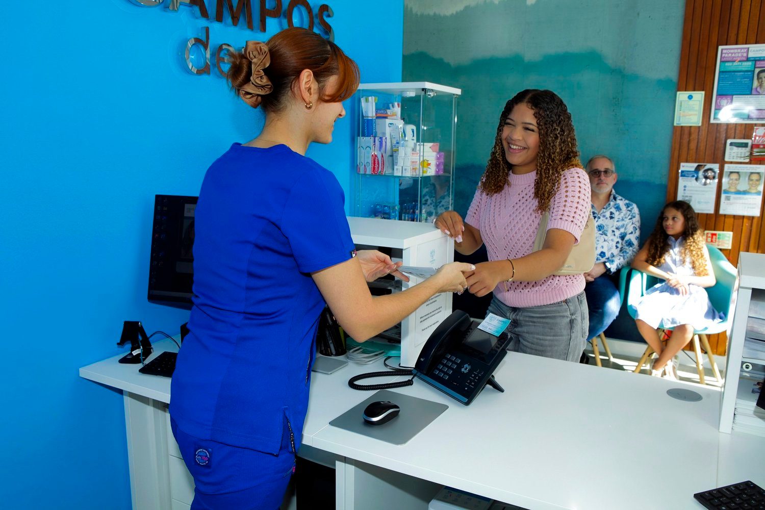 Friendly Campos Dental reception team welcoming a patient at the front desk